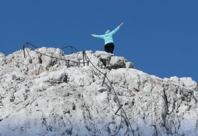 Una donna sulla cima di una montagna con le braccia aperte