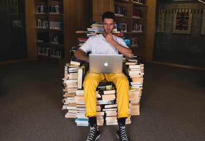 Persona seduta in una biblioteca su una sedia fatta di libri