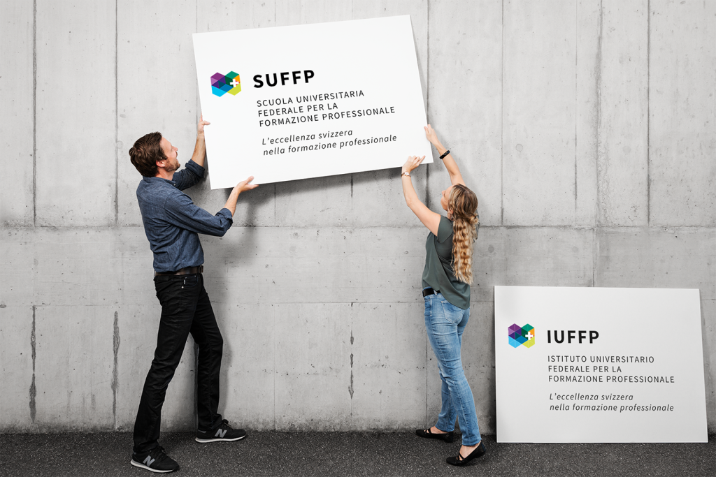 un uomo e una donna reggono un cartello con il nuovo nome HEFP