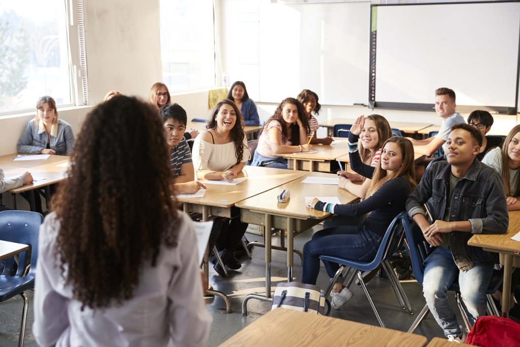 Vista posteriore di un'insegnante di scuola superiore di sesso femminile in piedi davanti alla classe che insegna una lezione